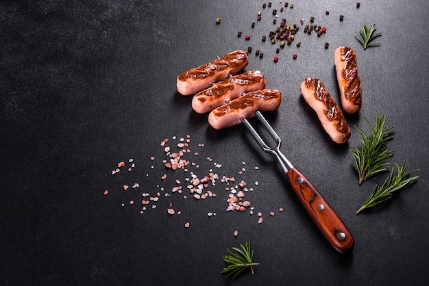 Tasty, fresh sausages grilled with vegetables spices and herbs. Photo of the finished dish on a dark concrete table