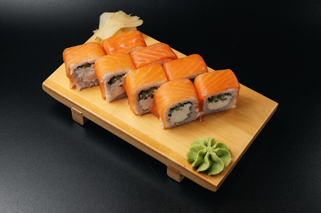 Tasty fresh sushi rolls with salmon on wooden plate