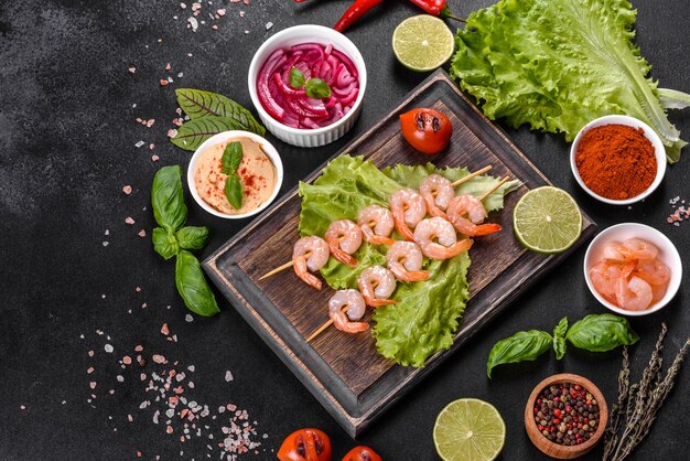 Tasty freshly prepared shrimp with spices and herbs on a wooden board on a dark concrete background. Seafood, healthy food