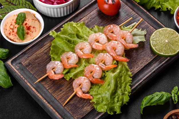 Tasty freshly prepared shrimp with spices and herbs on a wooden board on a dark table. Seafood, healthy food