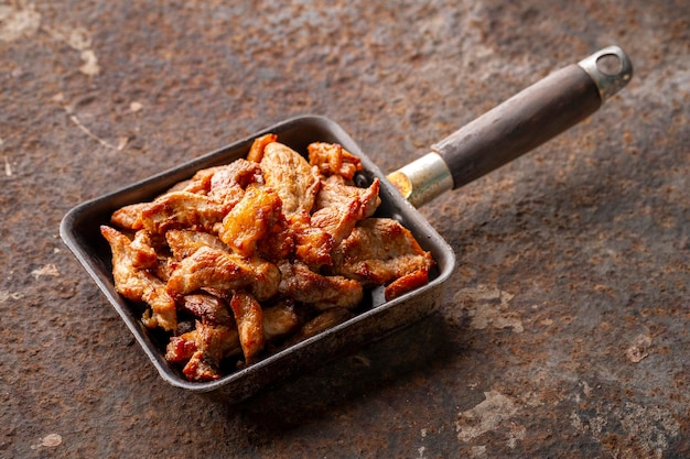 Gustoso filetto di maiale fritto in una vecchia padella su sfondo texture arrugginita