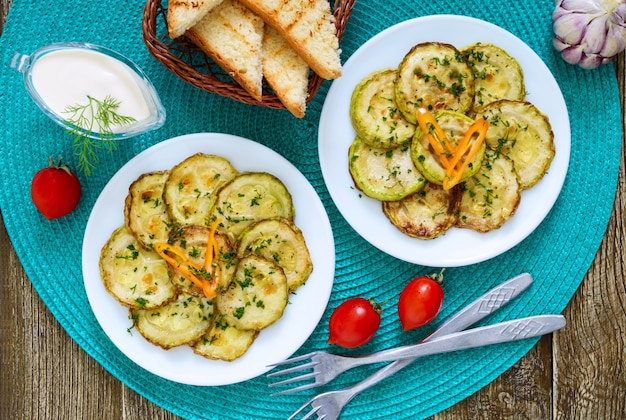 Tasty fried zucchini slices on a plate with sauce on a wooden table. Picnic snack. Rustic style. Top view, flat lay.