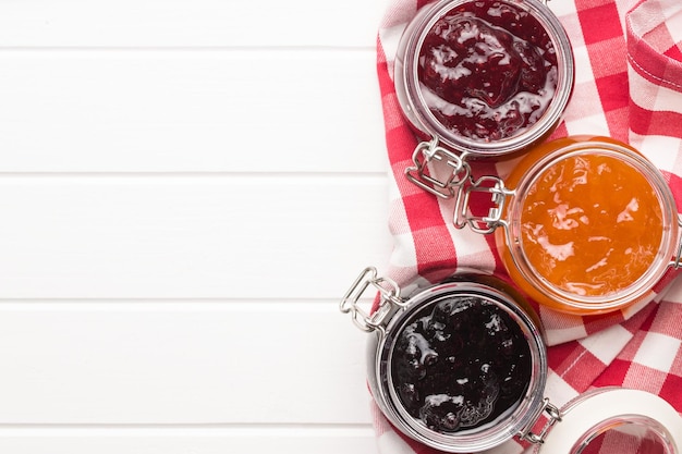 Photo tasty fruity jam in jar on white table