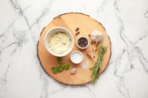 Tasty garlic butter and ingredients on light background