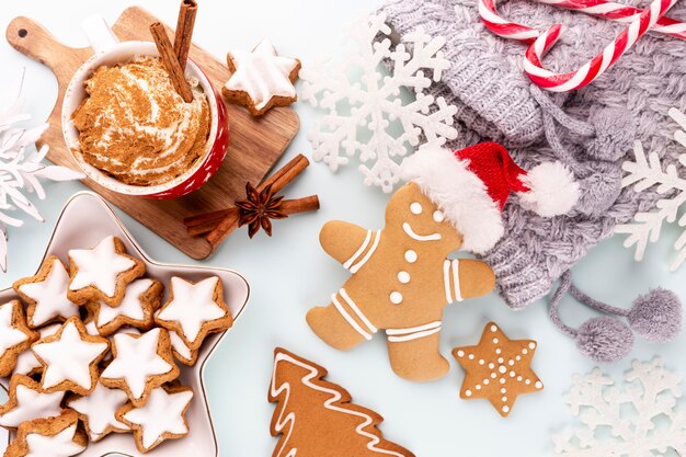 Tasty gingerbread cookies and Christmas decor on pastel background.