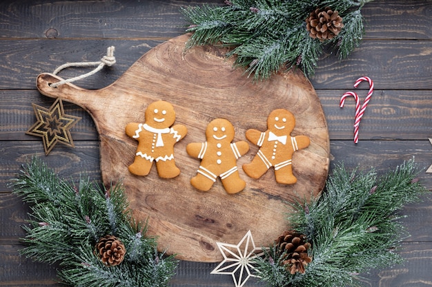 Tasty gingerbread cookies and Christmas decor on wooden background.