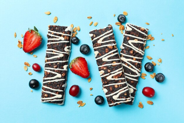 Tasty granola bars on blue background, top view