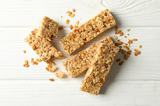 Tasty granola bars on white wooden background