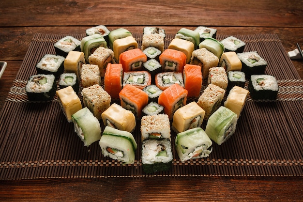 Tasty great colorful set of fresh japanese sushi maki rolls served on brown straw mat, close up. Food art, traditional seafood, luxury restaurant menu photo.