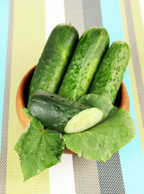 明るい背景に木製のボウルにおいしい緑のきゅうり