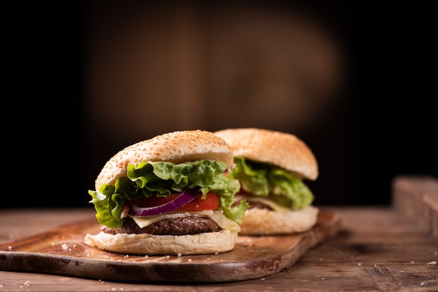 Вкусный гамбургер из говядины на гриле с салатом, сыром и луком, подается на разделочной доске с Copyspace