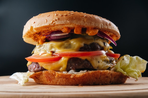 Tasty grilled big cheeseburger on wooden board Close up Premium Photo