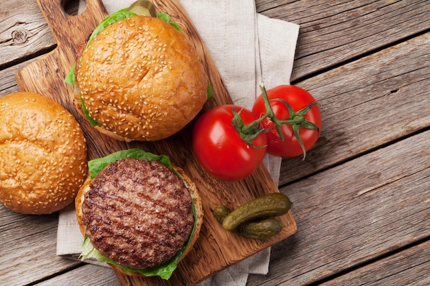 Tasty grilled home made burgers cooking with beef tomato cheese cucumber and lettuce Top view with space for your text