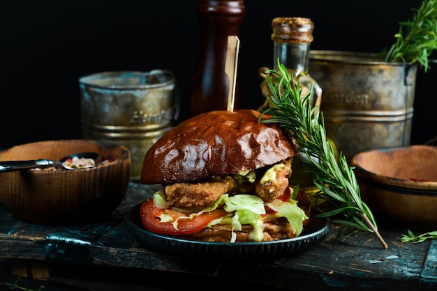 검은 배경에 손에 치킨 찹 토마토와 양파를 곁들인 맛있는 구운 집에서 만든 버거