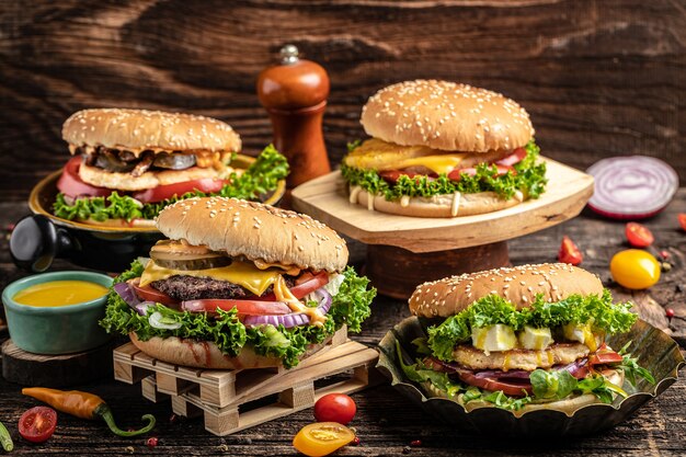 Gustosi hamburger fatti in casa alla griglia con manzo, pomodoro, formaggio, pancetta e lattuga su fondo di legno rustico. fast food e concetto di cibo spazzatura