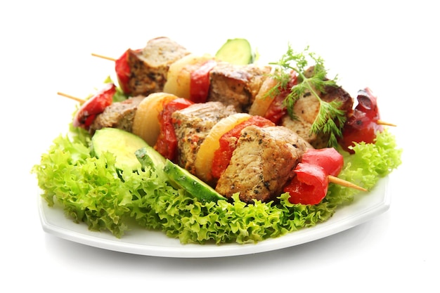 Tasty grilled meat and vegetables on skewers on plate isoalted on white