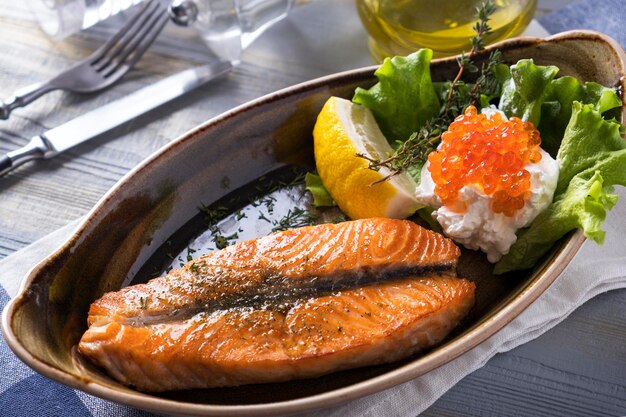 Tasty grilled salmon fillet with cream and caviar on a plate Closeup