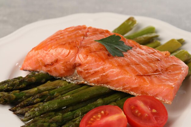 Foto delizioso salmone alla griglia con pomodori e asparagi sul piatto da vicino