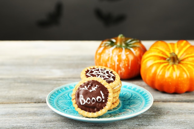 Tasty Halloween cookies on plate on wooden table