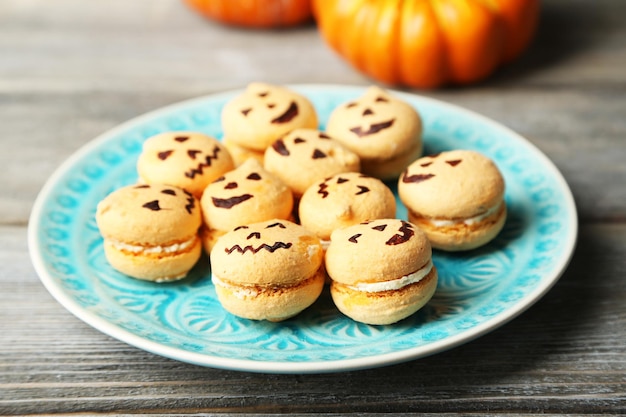 Tasty Halloween macaroons on plate on wooden table