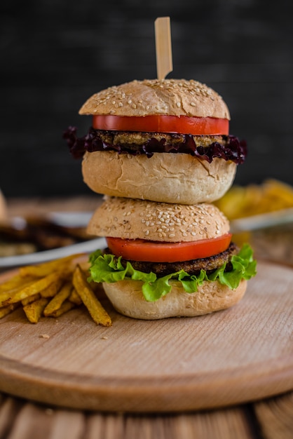 Tasty hamburger with meat and vegetables against a dark background. Fast food. It can be used as a background