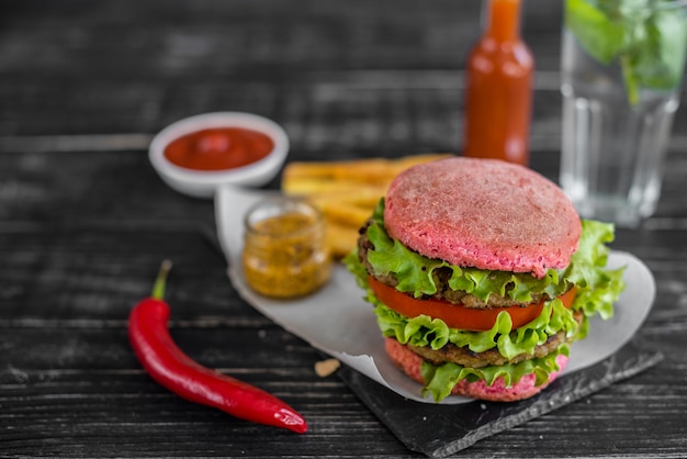 Tasty hamburger with meat and vegetables against a dark background. Fast food. It can be used as a background