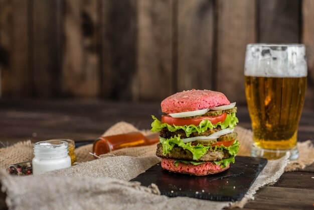 Tasty hamburger with meat and vegetables against a dark background