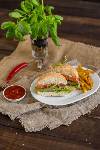 Tasty hamburger with meat and vegetables against a dark background