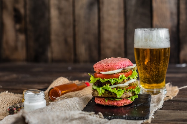 Tasty hamburger with meat and vegetables against a dark background