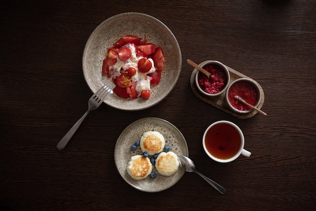 Tasty and healthy breakfast Tea with jam cheese pancakes burrata salad with tomatoes