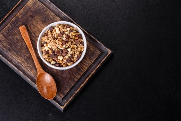 Tasty healthy breakfast with cereals granola chocolate milk and jam on a dark concrete background