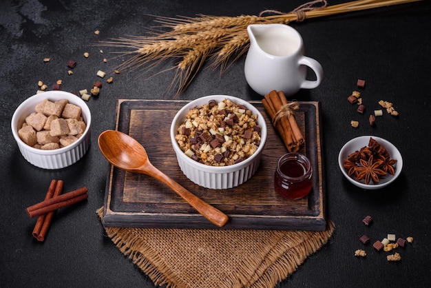 Tasty healthy breakfast with cereals granola chocolate milk and jam on a dark concrete background