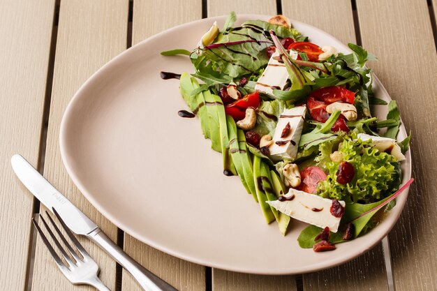 Tasty and healthy salad with arugula, brie, cheese, avocado, cherry tomatoes, dry cranberry and cashews.