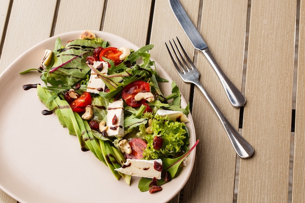 Tasty and healthy salad with arugula, brie, cheese, avocado, cherry tomatoes, dry cranberry and cashews.