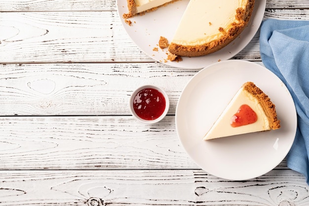 딸기 잼이 있는 흰색 나무 테이블에 있는 맛있는 수제 치즈 케이크