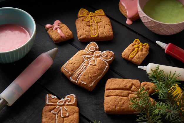 Tasty homemade cookies with icing on dark table with fir branch. Christmas and winter concept Close up