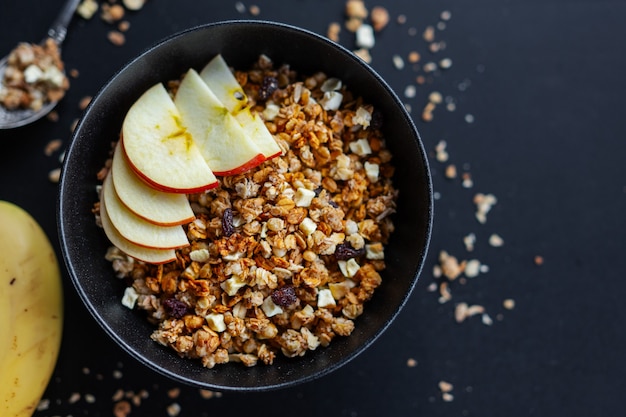 Tasty homemade fruity muesli granola served in bowl on dark background. Closeup