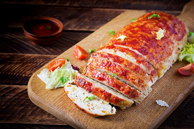 Tasty homemade ground baked turkey meatloaf with corn and slices pumpkin on wooden table