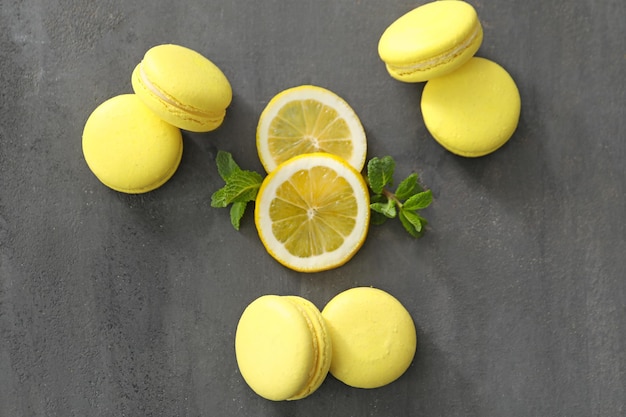 Tasty homemade lemon macarons and sliced fresh fruit on table