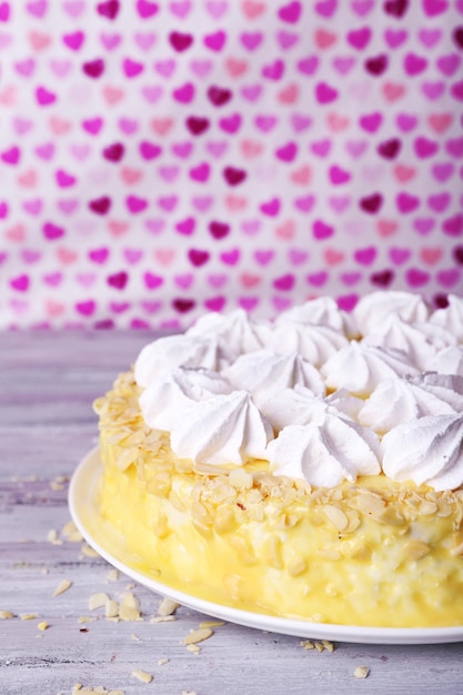 Tasty homemade meringue cake on wooden table, on pink background