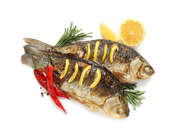 Tasty homemade roasted crucian carps with rosemary lemon and chili peppers on white background top view River fish