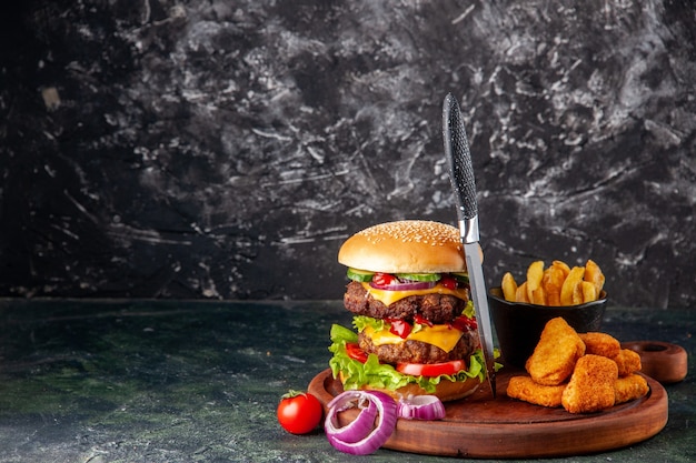 Tasty homemade sandwich tomatoes pepper on wooden cutting board onions tomato with stem chicken nuggets fries on the left side on dark color surface