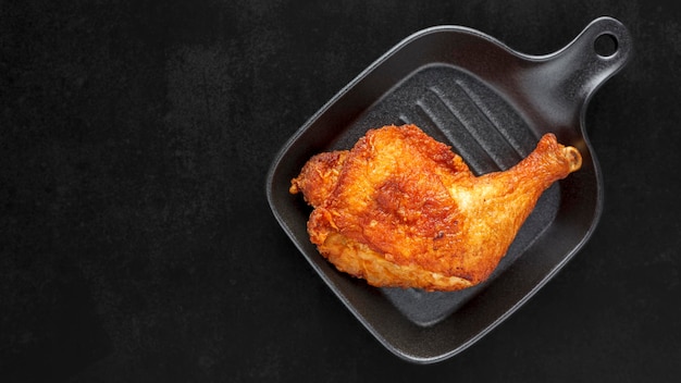 Photo tasty hot fried chicken in black skillet pan on dark tone texture background with copy space for text top table view flat lay