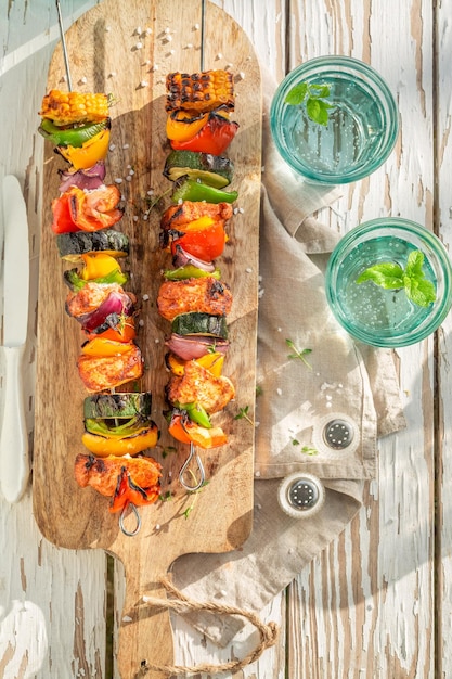 Tasty and hot grilled skewers served with citrus water in garden Grilled skewers on the grill