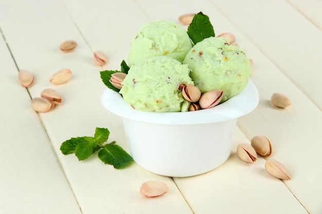 Tasty ice cream scoops in bowl on wooden table