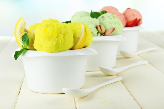 Tasty ice cream scoops in bowls on wooden table