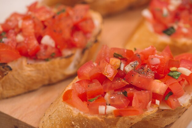 Tasty Italian bruschetta with  bread topped with tomato and herbs on wooden board