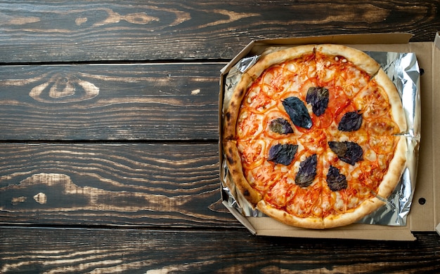 Gustosa pizza italiana in scatola su fondo di legno con copia spazio per il testo