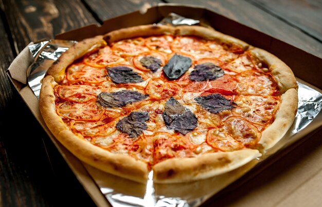 Tasty italian pizza in box on wood background