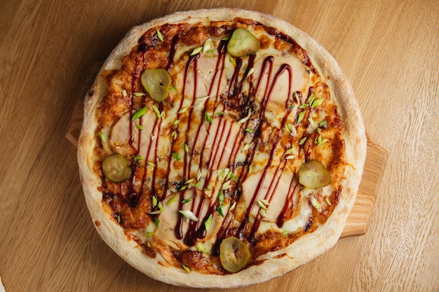 Tasty italian pizza with meat, pickles and sauce on wooden board